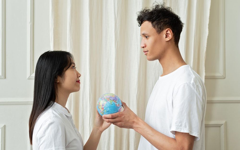 地球儀を手に向き合う男女(文化や価値観を話し合うイメージ)